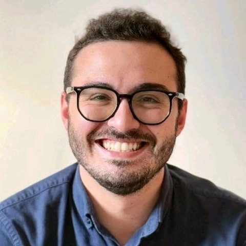 Artur Batissoco, fundador do PortfólioVivo, sorrindo, de óculos e camisa azul